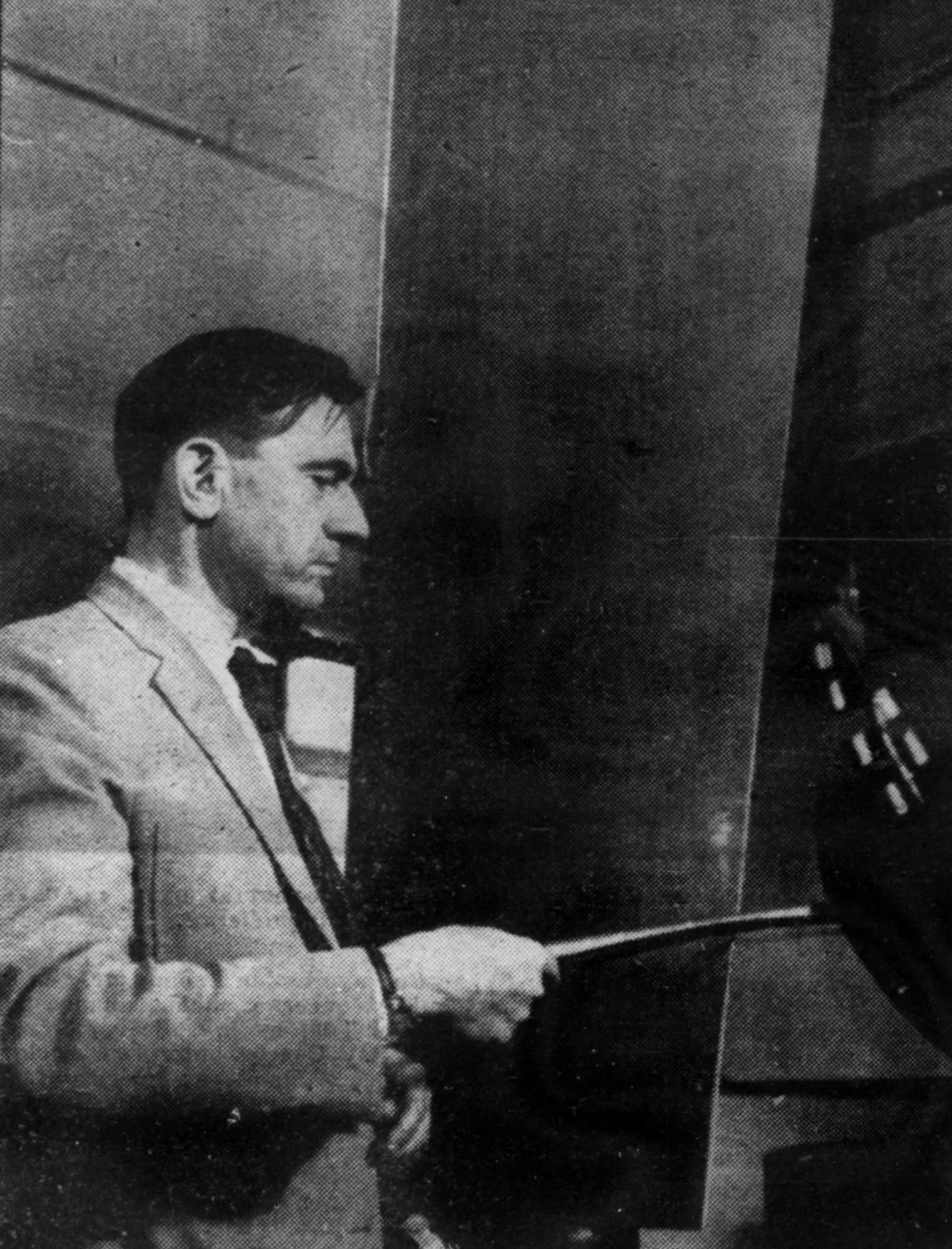 Чёрно-белая фотография: мужчина в пиджаке проводит металлическим смычком по краю стальной пластины.